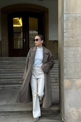 a lady wears a brown wrap coat with white top and white jeans